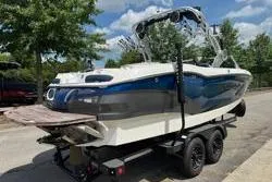 Slide: The Image of 2021 MasterCraft X24 boat on trailer, parked outdoors under cloudy sky. - 3