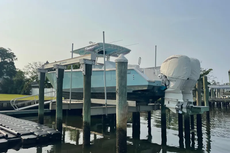 Slide: The Image of 2020 Jupiter 38 boat on lift at marina, twin engines covered, calm water. - 13