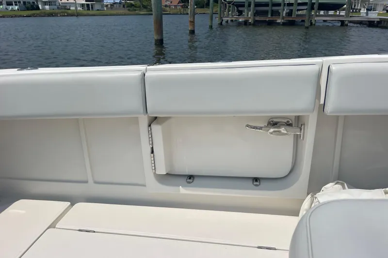 Slide: The Image of 2020 Jupiter 38 boat interior with white seating and storage compartment by the water. - 20
