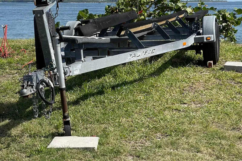 Slide: The Image of Trailer for 2006 Corsair Sprint 750 sailboat on grassy shore by water. - 16