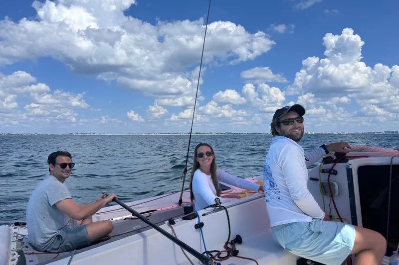 Slide: The Image of Three people sailing on a 2006 Corsair Sprint 750 under a blue sky. - 9