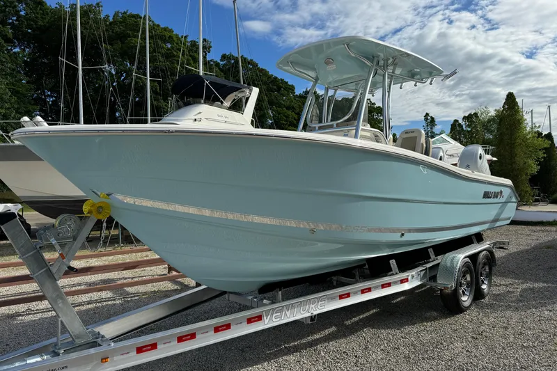 Slide: The Image of 2024 Bulls Bay 255 boat on trailer, parked outdoors under a partly cloudy sky. - 1