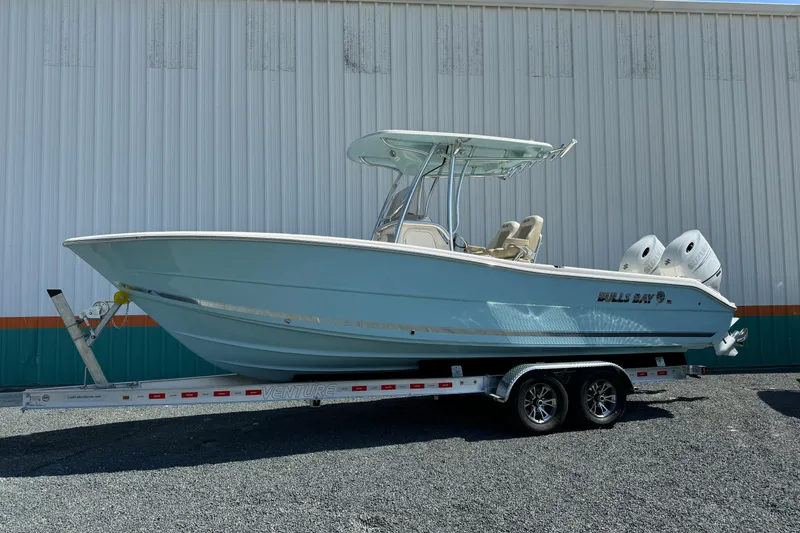 Slide: The Image of 2024 Bulls Bay 255 boat on trailer, parked outdoors near a building. - 2