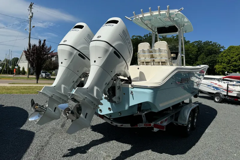 Slide: The Image of 2024 Bulls Bay 255 boat with dual outboard engines on a trailer, parked outdoors. - 5