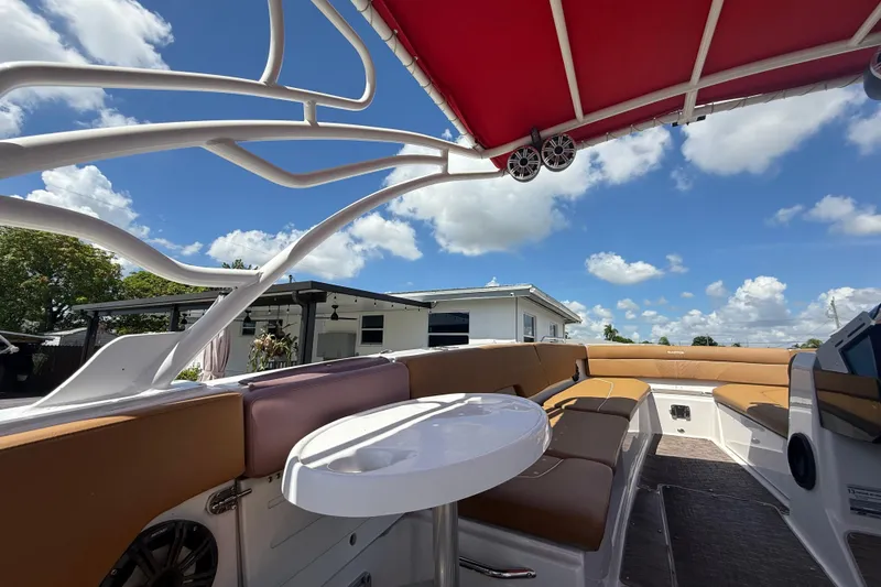 Slide: The Image of 2019 Glastron GTD 220 boat interior with red canopy and seating under blue sky. - 20
