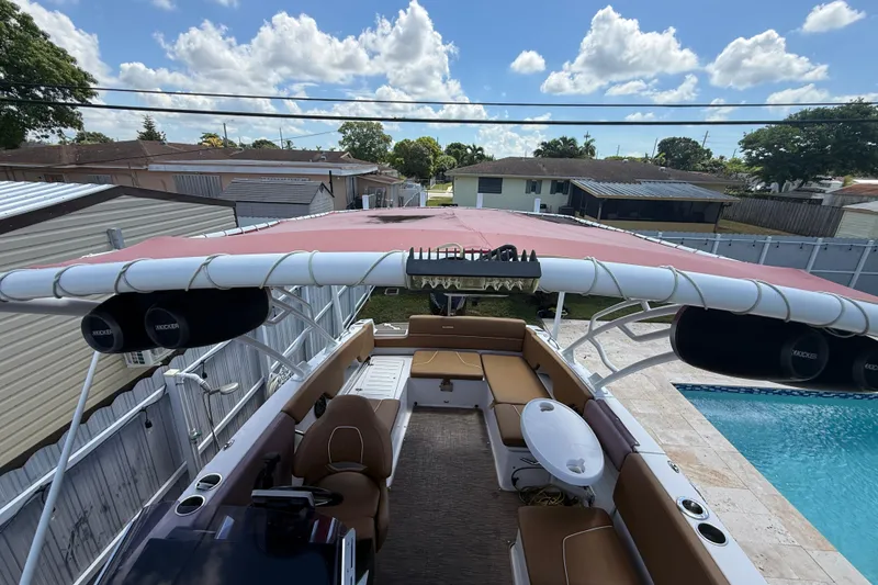 Slide: The Image of 2019 Glastron GTD 220 boat with red canopy, poolside view, and outdoor speakers. - 27