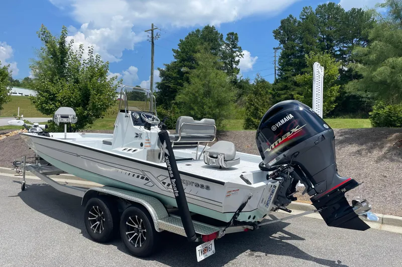Slide: The Image of 2023 Express H22 boat with Yamaha outboard motor on a trailer, parked outdoors. - 4