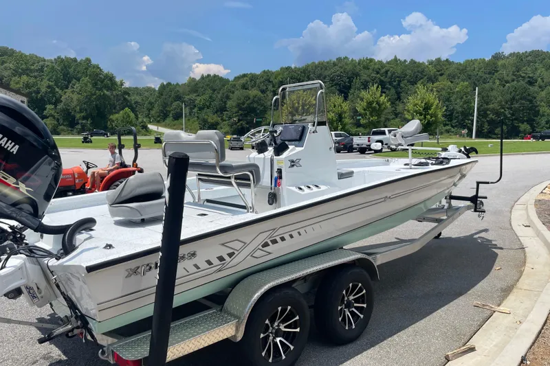 Slide: The Image of 2023 Express H22 boat on trailer, parked outdoors under a clear blue sky. - 9