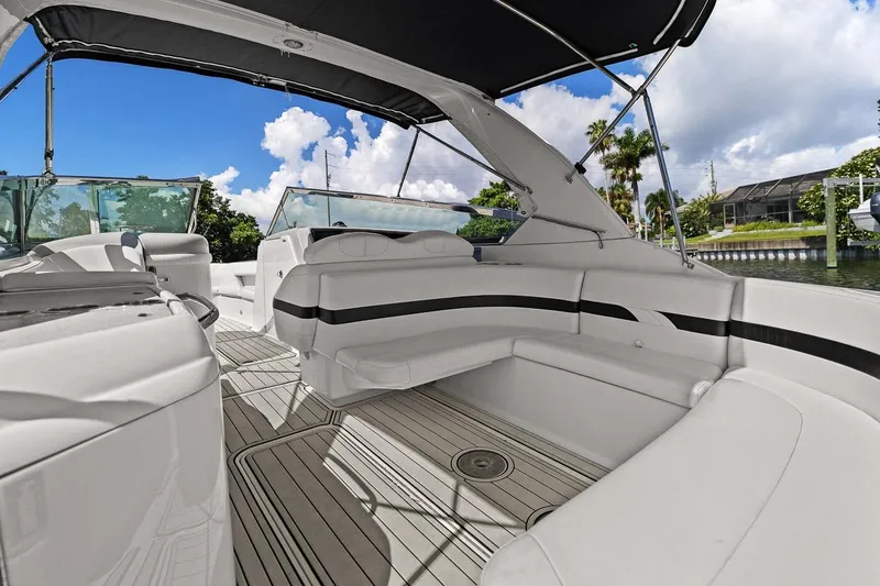Slide: The Image of 2007 Formula 280 Bowrider boat interior with white seating and canopy, docked by lush greenery. - 35