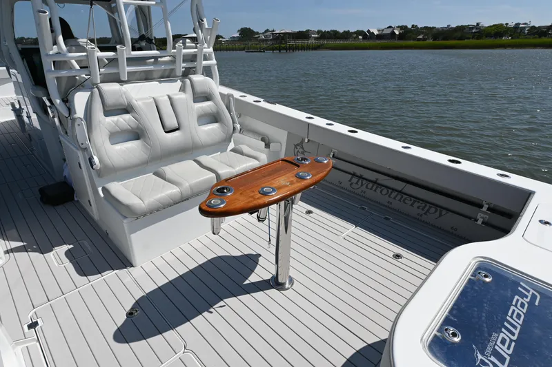 Slide: The Image of 2021 Freeman 37VH boat interior with white seating and wooden table on a calm water backdrop. - 26