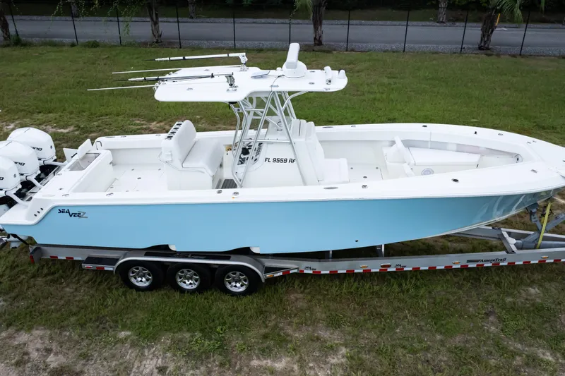Slide: The Image of 2017 SeaVee 340Z boat on trailer, light blue hull, triple engines, parked on grass. - 45