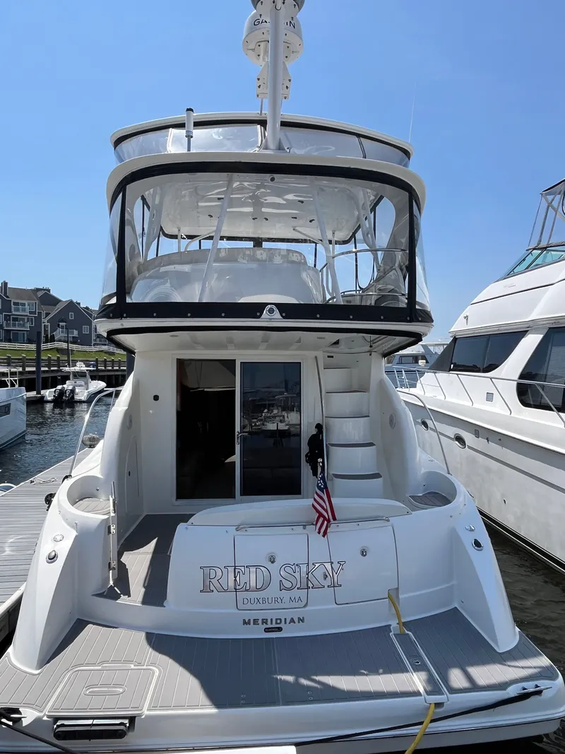 Slide: The Image of 2008 Meridian 391 Sedan yacht docked, rear view with American flag and "Red Sky" name. - 2