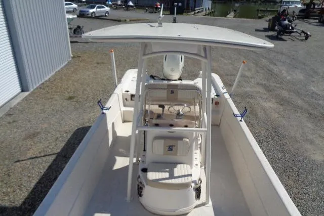Slide: The Image of 2018 Carolina Skiff 258 DLV boat with T-top, parked on gravel. - 12