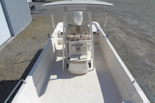 Slide: The Image of 2018 Carolina Skiff 258 DLV boat with center console and T-top, parked on gravel. - 13