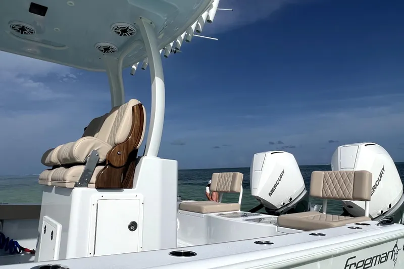 Slide: The Image of 2024 Freeman 28 boat with Mercury engines, luxurious seating, and ocean backdrop. - 10