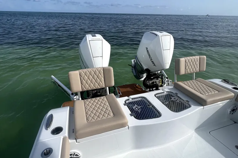 Slide: The Image of 2024 Freeman 28 boat with dual Mercury engines, cushioned seating, and ocean backdrop. - 12