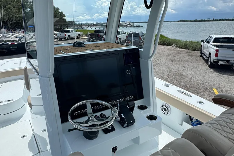 Slide: The Image of 2024 Freeman 28 boat dashboard with steering wheel and control panel by the waterfront. - 27