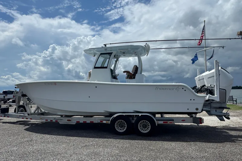 Slide: The Image of 2024 Freeman 28 boat on trailer under cloudy sky, featuring dual engines. - 36