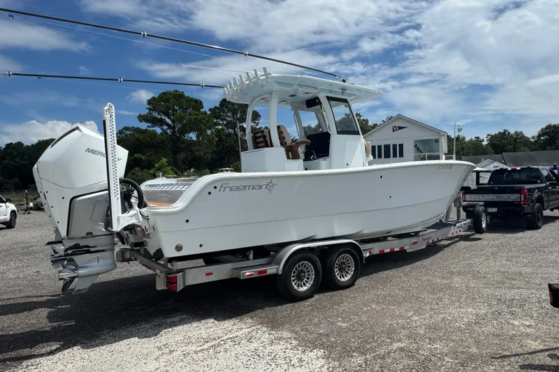 Slide: The Image of 2024 Freeman 28 boat on trailer, parked outdoors under a partly cloudy sky. - 40
