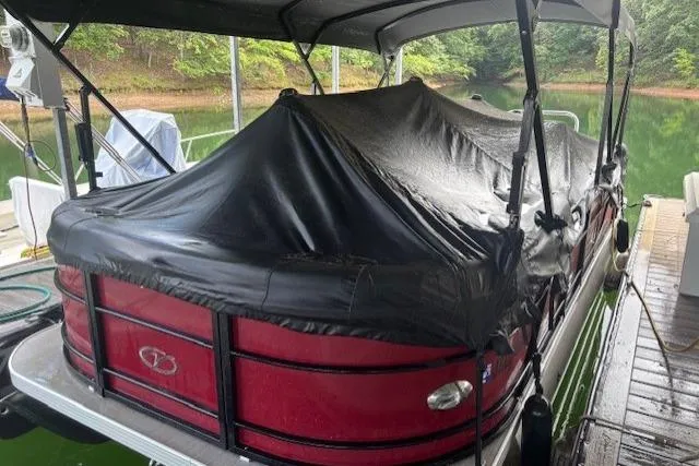 Slide: The Image of 2023 Veranda Relax VR22RC pontoon boat covered at a dock, surrounded by greenery. - 21