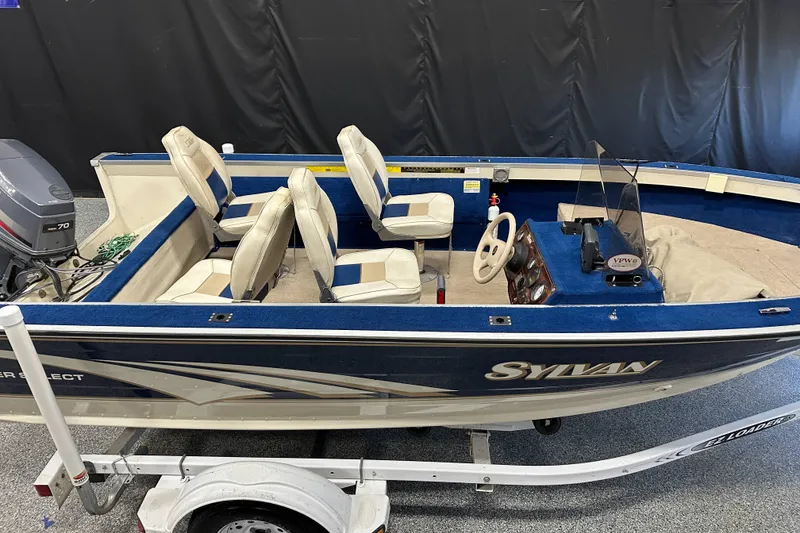 Slide: The Image of 1997 Sylvan 16 Super Select boat with blue interior and outboard motor on trailer. - 15