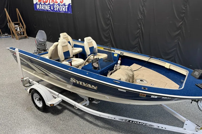 Slide: The Image of 1997 Sylvan 16 Super Select boat on trailer, displayed indoors at a marine shop. - 17