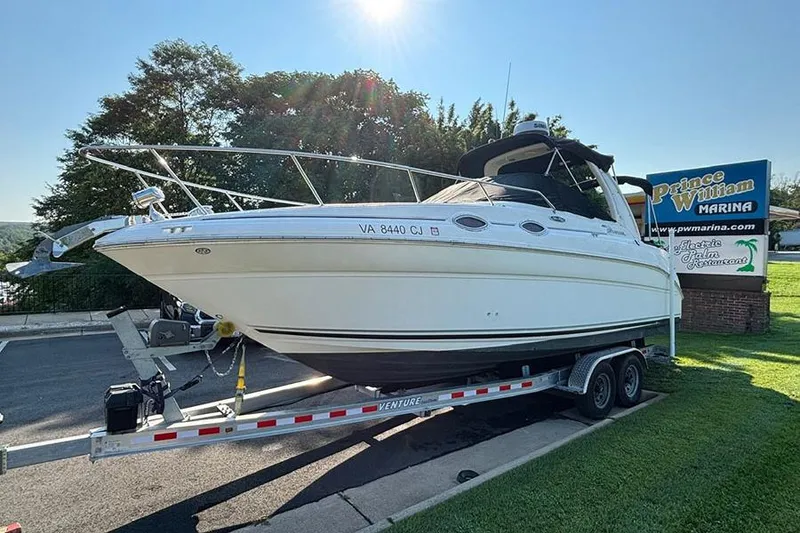 The Image of 2004 Sea Ray 260 Sundancer boat on trailer, parked outdoors under clear blue sky. - 0