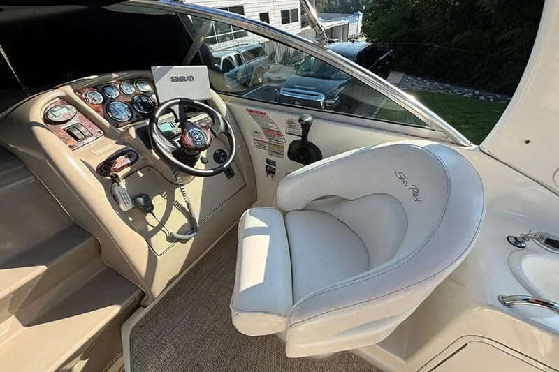 Slide: The Image of 2004 Sea Ray 260 Sundancer helm with steering wheel, gauges, and white captain's chair. - 10