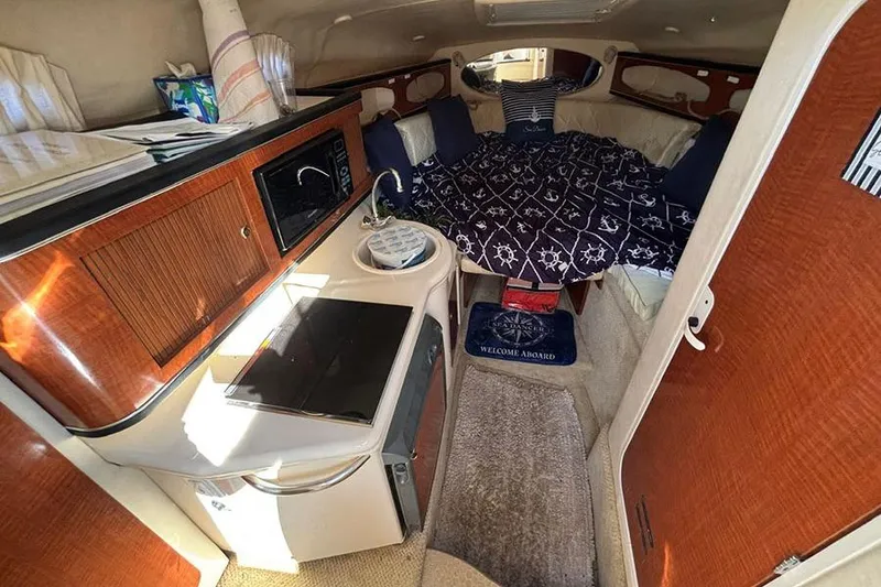 Slide: The Image of 2004 Sea Ray 260 Sundancer cabin interior with kitchenette and cozy sleeping area. - 18