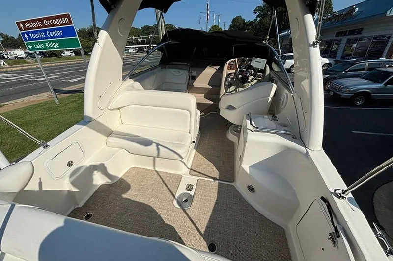 Slide: The Image of 2004 Sea Ray 260 Sundancer boat interior with seating and steering wheel, parked near road signs. - 4