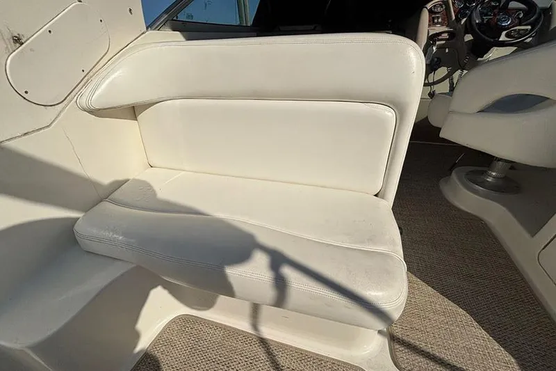Slide: The Image of 2004 Sea Ray 260 Sundancer boat interior with white seating and steering area. - 8