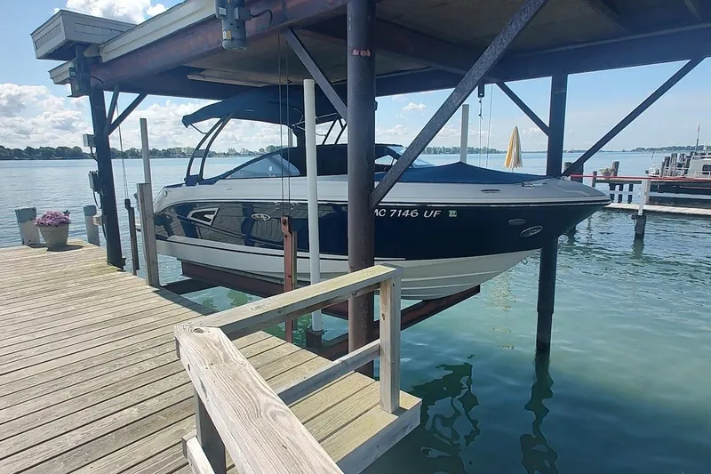 Slide: The Image of 2017 Sea Ray SLX 230 boat docked on a lift over calm water. - 0