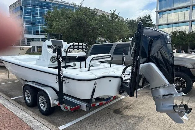Slide: The Image of 2026 Yellowfin 24 CE boat on trailer, parked outdoors near modern buildings. - 16