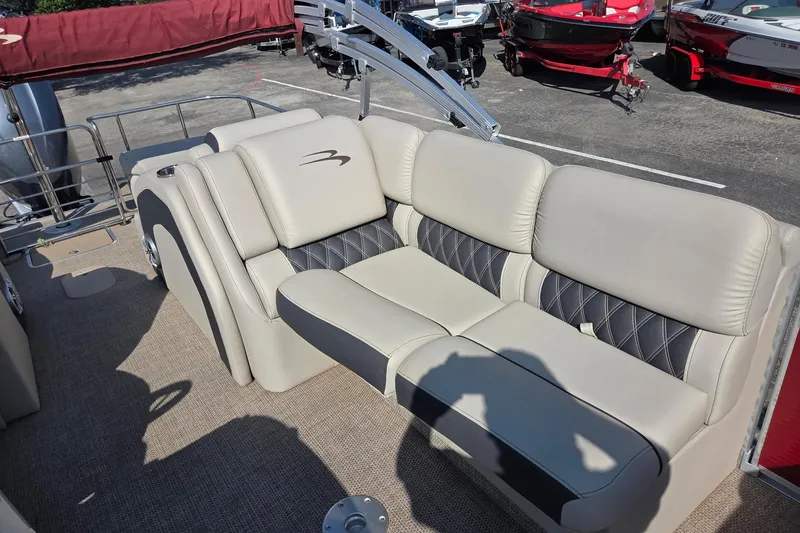 Slide: The Image of 2019 Bennington Q 25 QCW boat with beige and black seating, parked outdoors. - 5