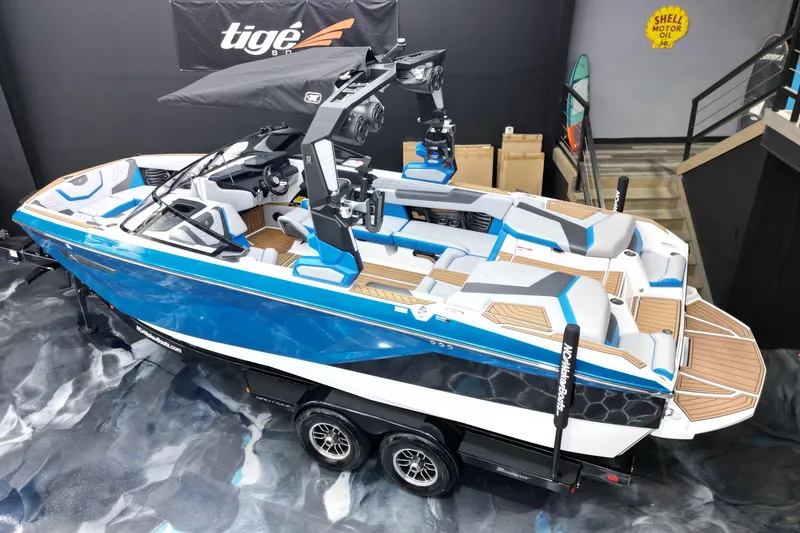 Slide: The Image of 2022 Nautique Super Air Nautique G23 boat, blue and white, displayed indoors on a trailer. - 6