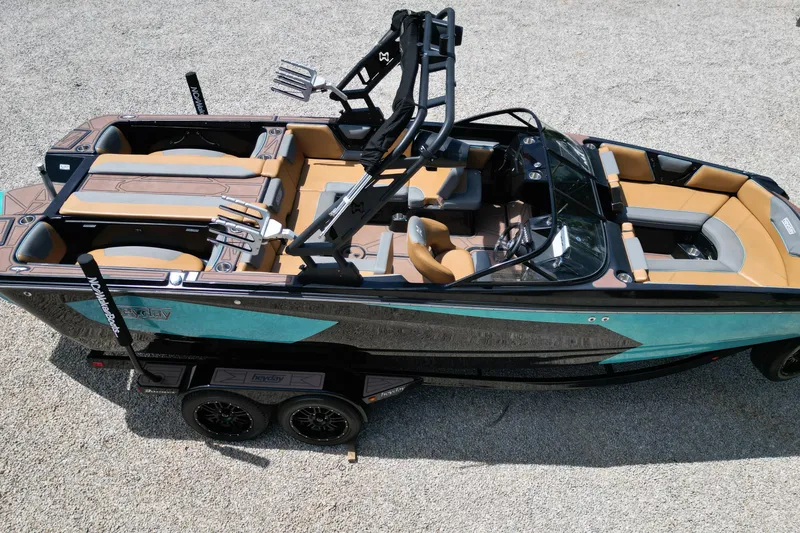 Slide: The Image of 2022 Heyday WTSurf boat with tan and gray seating, black frame, and teal accents on a trailer. - 14