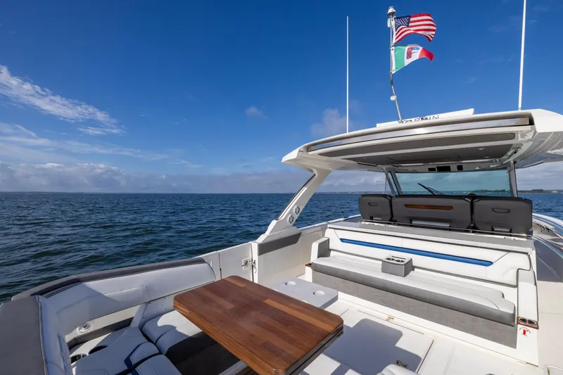 Slide: The Image of 2021 Tiara Yachts 43 LS, luxury deck view, ocean backdrop, flags waving, clear blue sky. - 15