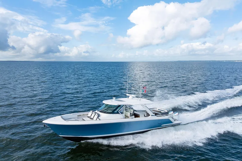 Slide: The Image of 2021 Tiara Yachts 43 LS cruising on open water under a clear blue sky. - 57