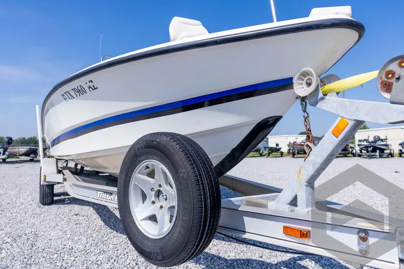 Slide: The Image of 2008 Triton 240 LTS boat on trailer, parked on gravel under clear blue sky. - 10
