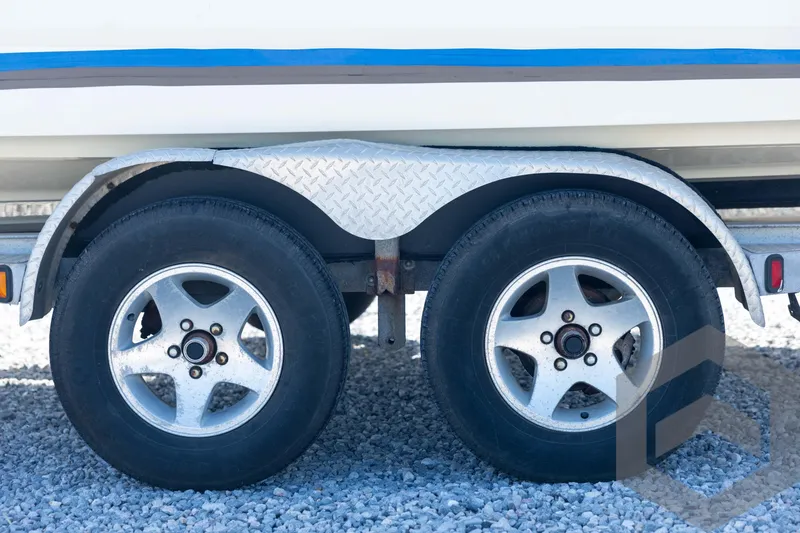 Slide: The Image of Trailer wheels of a 2008 Triton 240 LTS boat on gravel surface. - 24