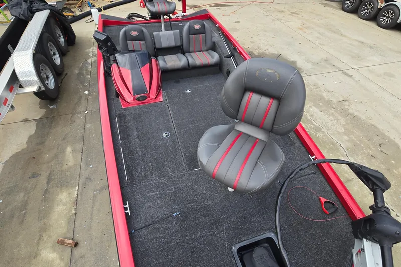 Slide: The Image of 2013 Ranger RT188 fishing boat interior with red and gray seating, parked on concrete. - 10