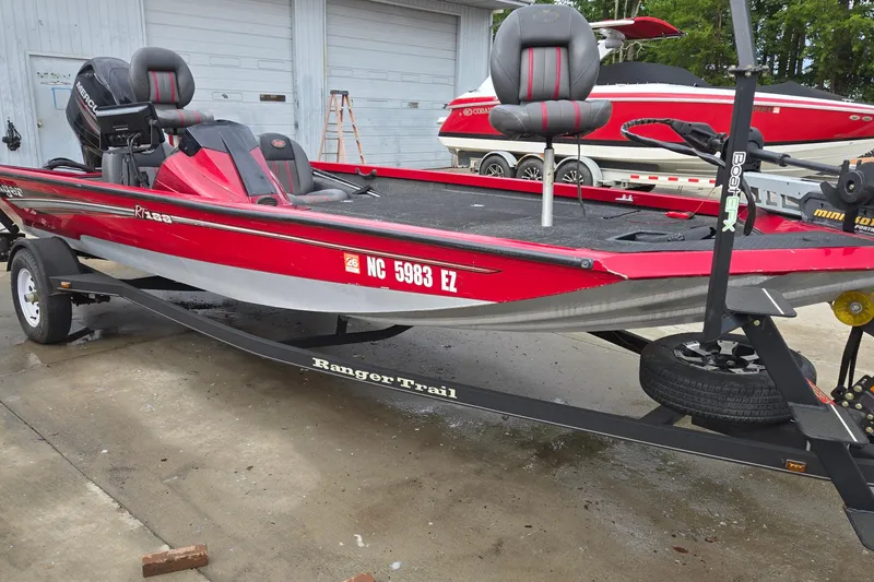 Slide: The Image of Red 2013 Ranger RT188 boat on trailer, parked outdoors near a garage. - 3