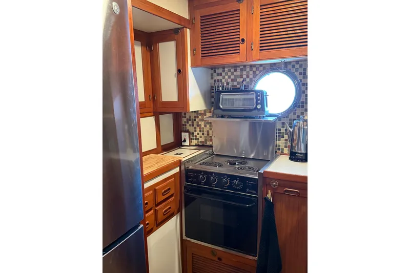 Slide: The Image of Compact galley kitchen in 1994 Kadey-Krogen Krogen 42 yacht with stove, toaster oven, and porthole. - 3