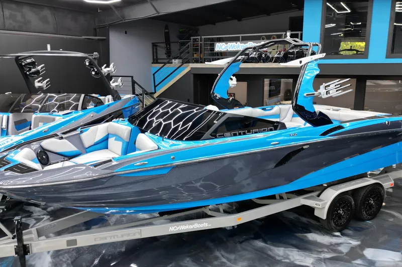 Slide: The Image of 2020 Centurion Fi25 boat in showroom, featuring sleek blue and gray design on trailer. - 3