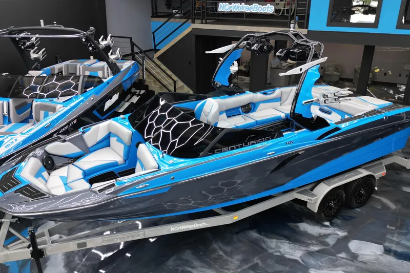 Slide: The Image of 2020 Centurion Fi25 boat in showroom, featuring sleek blue and gray design on trailer. - 4