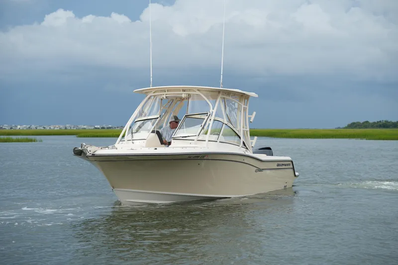 Slide: The Image of 2018 Grady-White Freedom 235 boat cruising on calm waters under cloudy skies. - 15