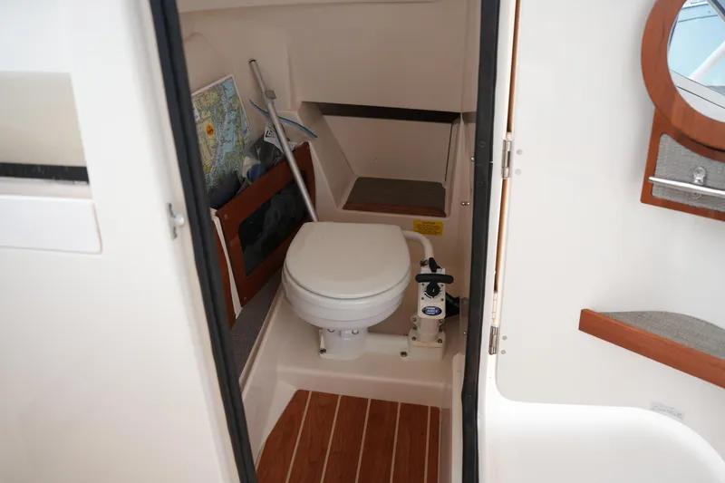 Slide: The Image of 2018 Grady-White Freedom 235 boat interior with compact marine toilet and wooden flooring. - 21