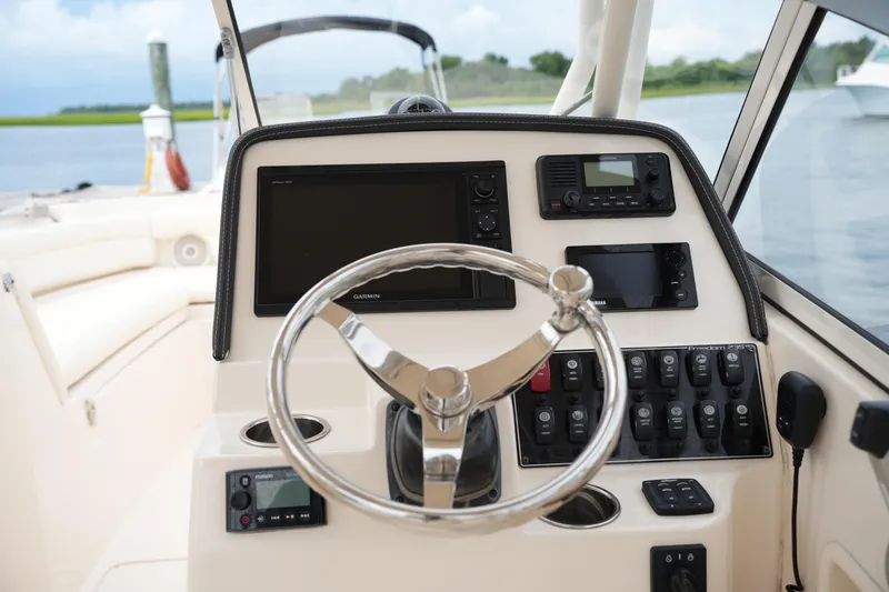 Slide: The Image of 2018 Grady-White Freedom 235 boat dashboard with steering wheel and navigation controls. - 27