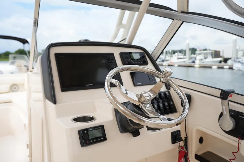 Slide: The Image of 2018 Grady-White Freedom 235 boat helm with steering wheel and navigation controls. - 28