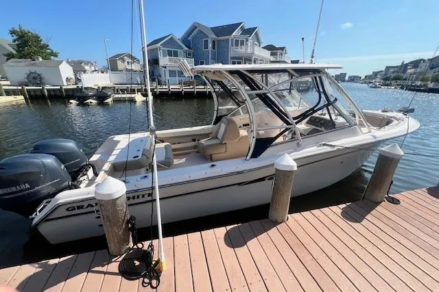 Slide: The Image of 2013 Grady-White Freedom 275 boat docked by waterfront homes on a sunny day. - 1